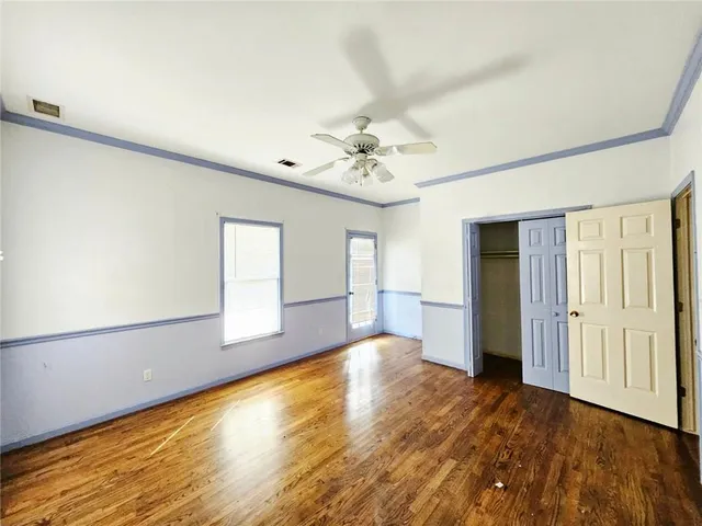 a view of an empty room with window and wooden floor