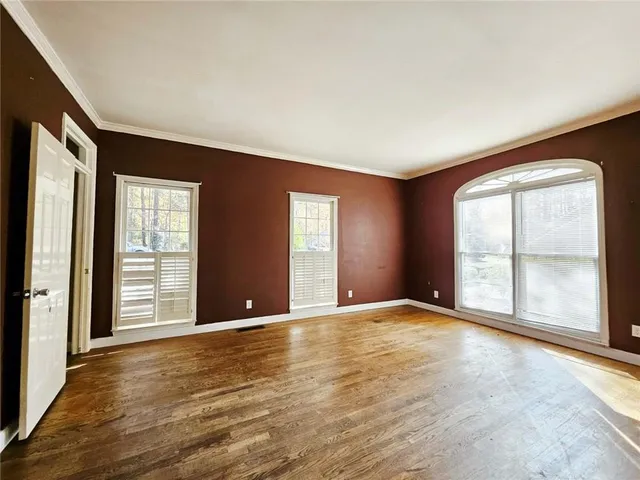 a view of an empty room with a window and wooden floor