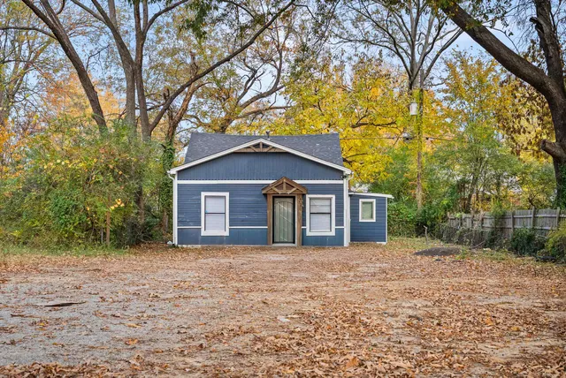 a front view of house with yard and trees in the background