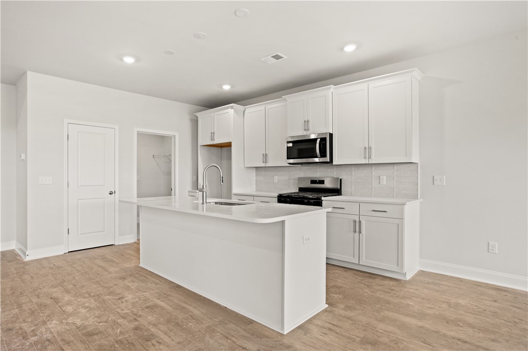 554 Hydrangea Street, Unit LOT 67 Seneca, SC 29678 - Photo 6 of 26 A well-appointed kitchen features stainless steel appliances, pristine white cabinetry, and a central island with a sink.
