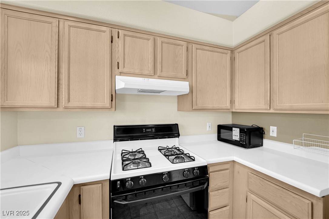 7572 Durham Hall Avenue, Unit 201 Las Vegas, NV 89130 - Photo 11 of 26 Kitchen with light brown cabinetry, gas stove, light countertops, and black microwave