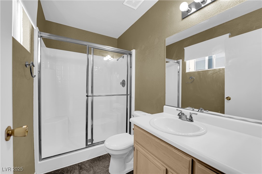 7572 Durham Hall Avenue, Unit 201 Las Vegas, NV 89130 - Photo 15 of 26 Full bathroom with a textured wall, a shower stall, vanity, and dark tile patterned floors