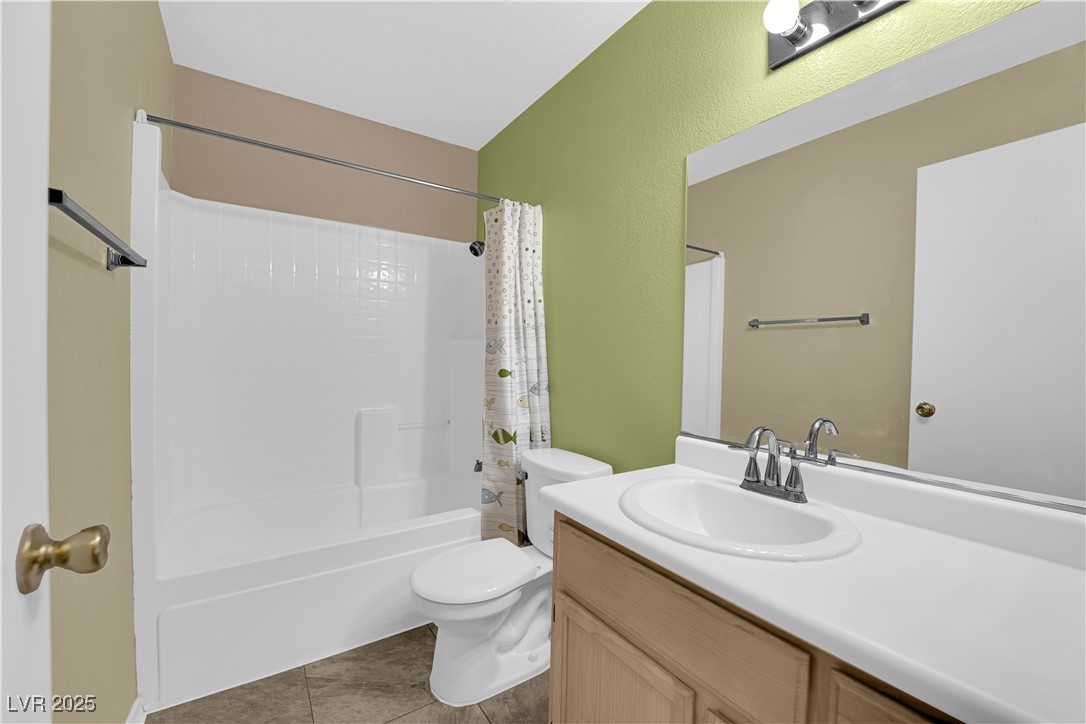 7572 Durham Hall Avenue, Unit 201 Las Vegas, NV 89130 - Photo 16 of 26 Bathroom featuring vanity, shower / bath combo with shower curtain, and light tile patterned floors