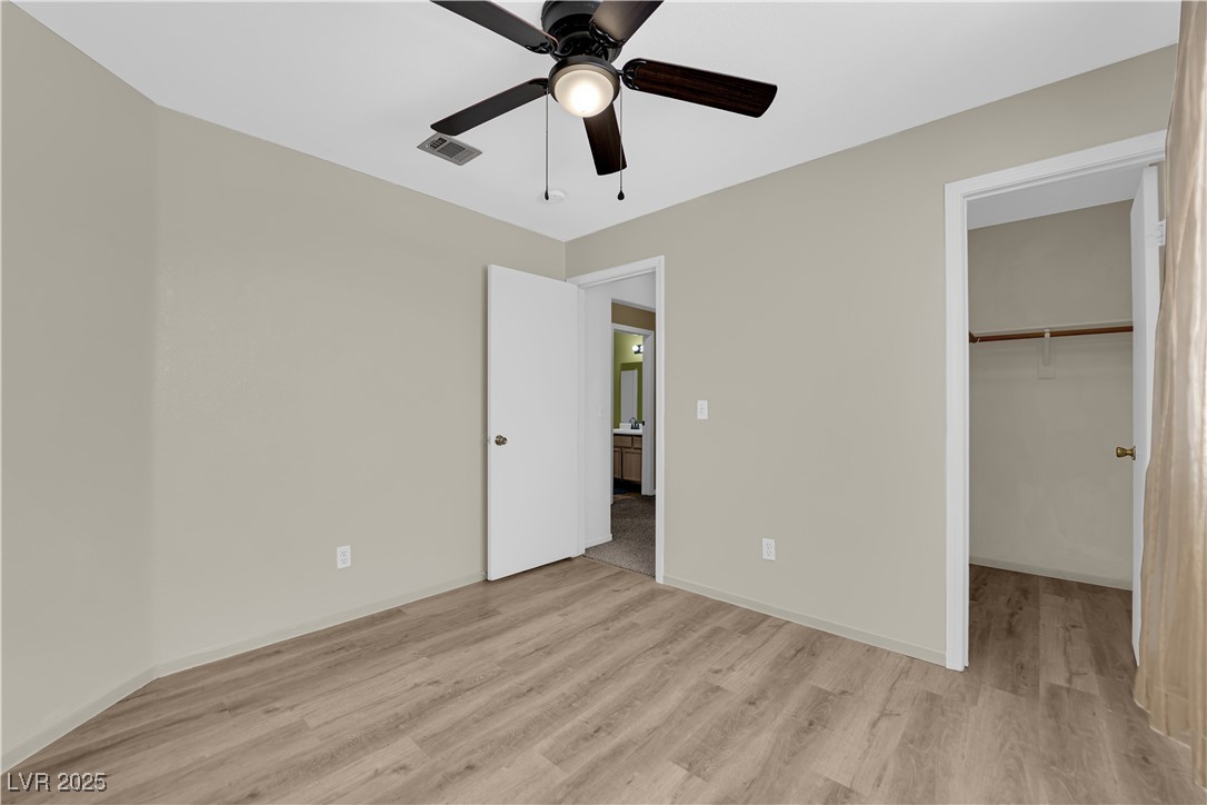 7572 Durham Hall Avenue, Unit 201 Las Vegas, NV 89130 - Photo 20 of 26 Unfurnished bedroom featuring a walk in closet, light wood finished floors, and ceiling fan