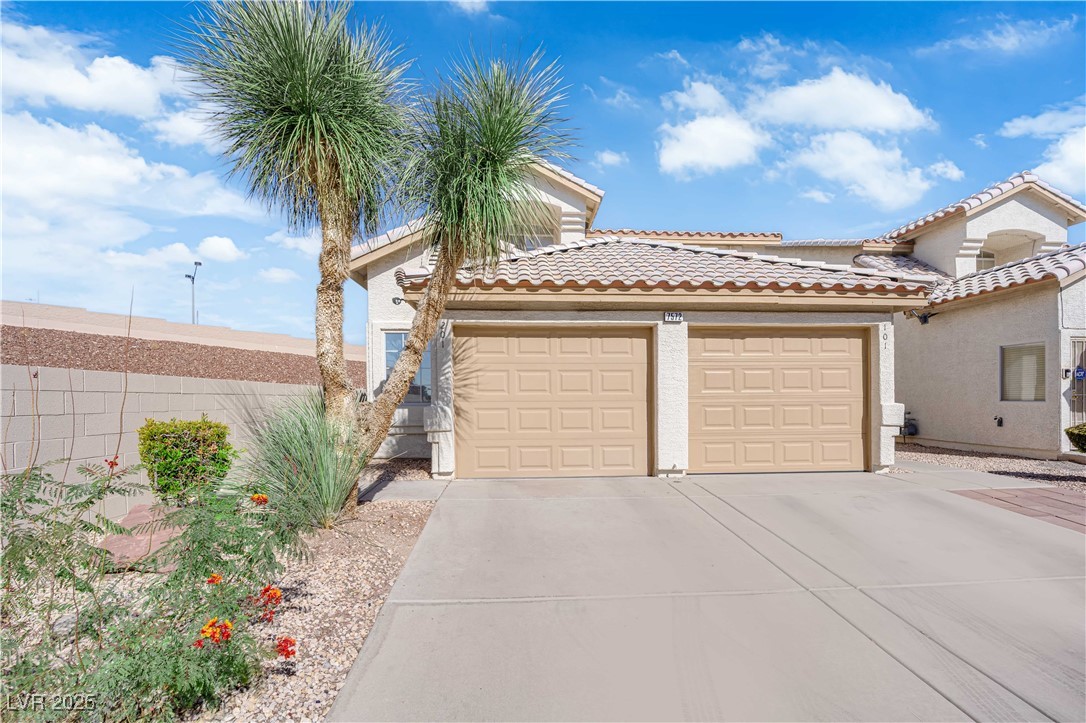 7572 Durham Hall Avenue, Unit 201 Las Vegas, NV 89130 - Photo 2 of 26 View of front of house with stucco siding, a garage, a tile roof, and concrete driveway