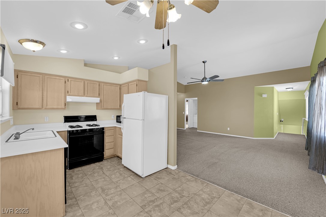 7572 Durham Hall Avenue, Unit 201 Las Vegas, NV 89130 - Photo 9 of 26 Kitchen featuring light brown cabinetry, freestanding refrigerator, light countertops, range with gas cooktop, and light colored carpet