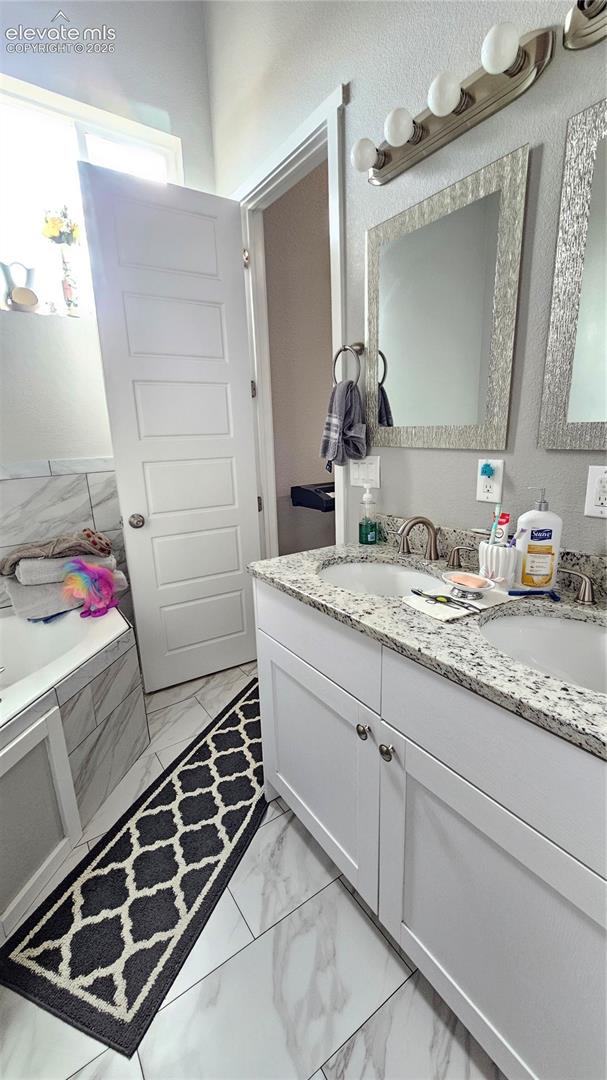 3835 Sengbeil Road Yoder, CO 80864 - Photo 25 of 48 Double vanity with undermount sinks and granite countertops, set against a backdrop of white-finish cabinetry
