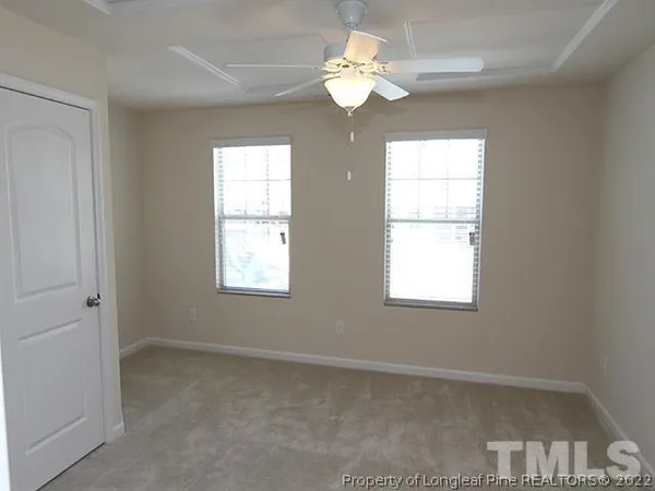 an empty room with windows and chandelier fan