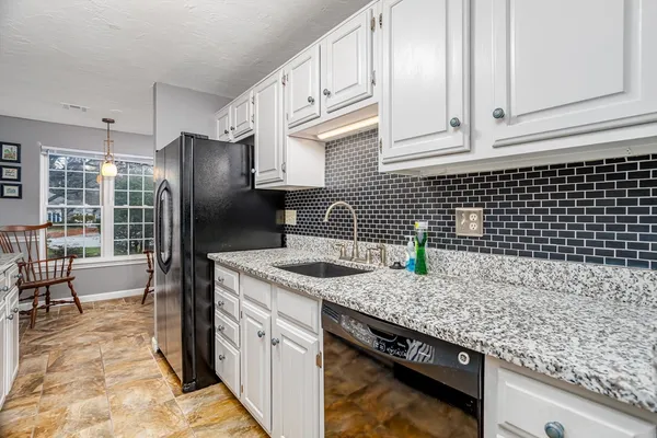 a kitchen with granite countertop a sink a stove and refrigerator