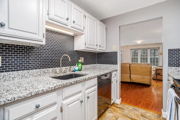 a kitchen with granite countertop a sink a stove and cabinets