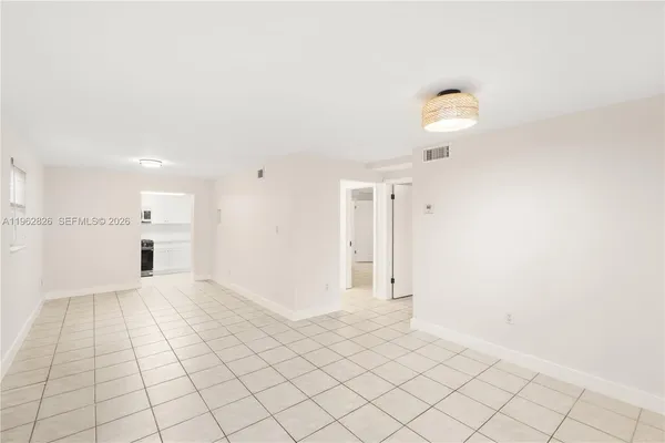 a view of an empty room and kitchen space with a sink
