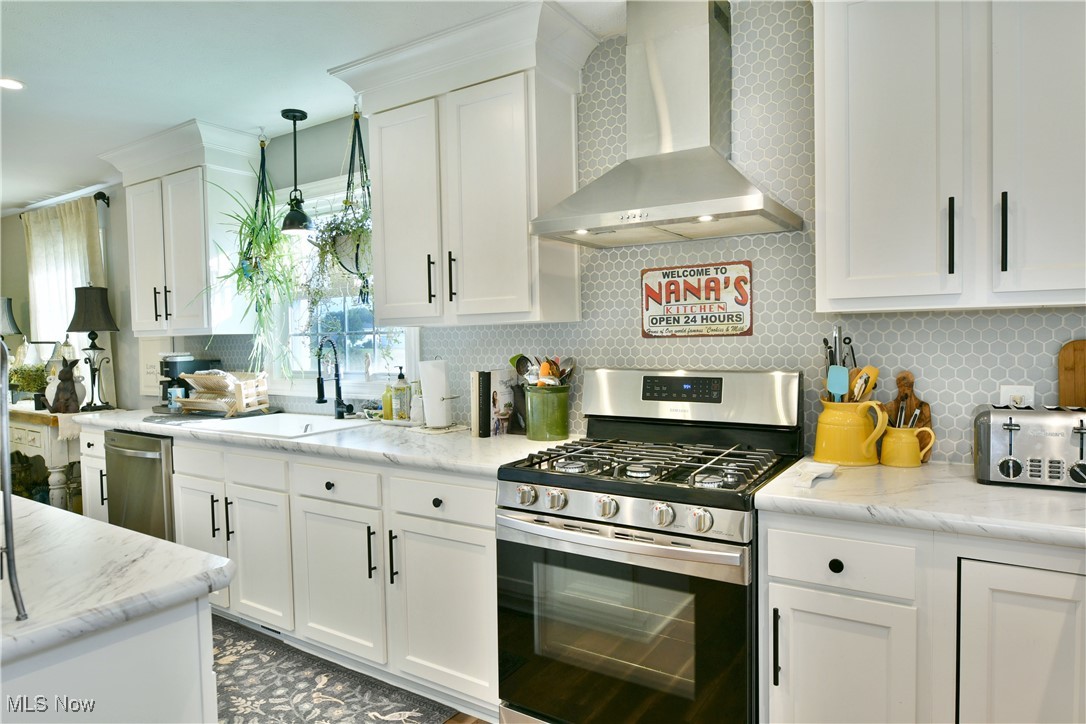 5558 Pierce Road Northwest Warren, OH 44481 - Photo 20 of 50 Kitchen featuring wall chimney exhaust hood, white cabinetry, stainless steel appliances, and tasteful backsplash