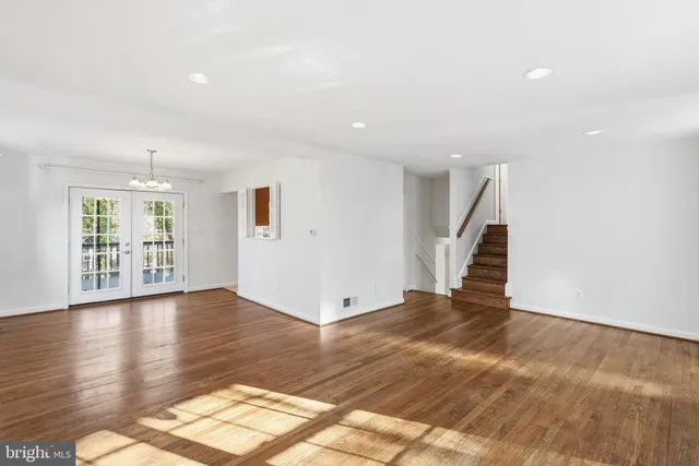 a view of an empty room with wooden floor and staircase