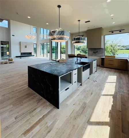 a large kitchen with stainless steel appliances kitchen island granite countertop a large counter top and a wooden floors