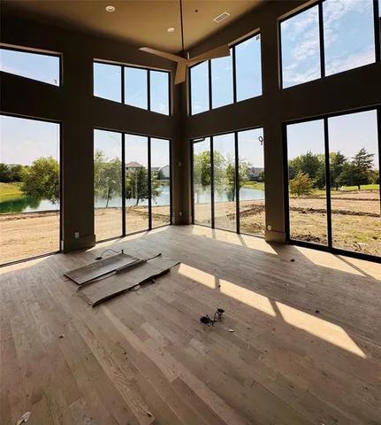a view of an empty room with wooden floor and windows