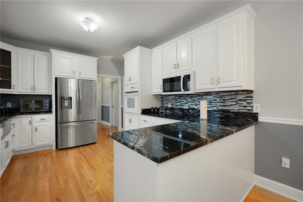 425 McDaniel Station Road Southwest Calhoun, GA 30701 - Photo 12 of 46 a kitchen with stainless steel appliances granite countertop a refrigerator a stove a sink and white cabinets