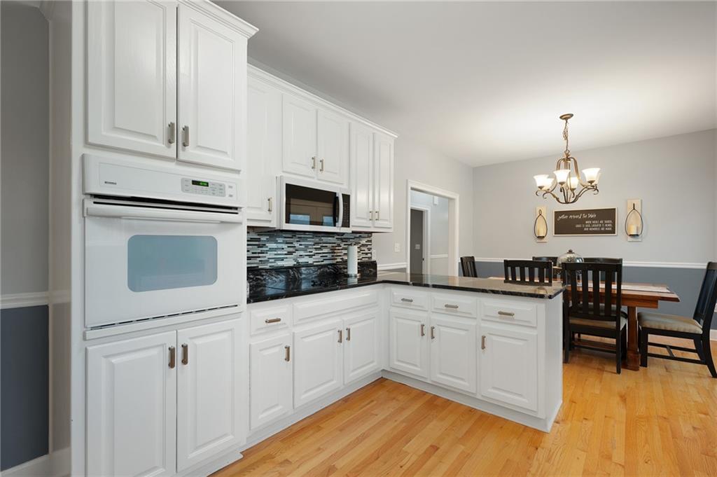 425 McDaniel Station Road Southwest Calhoun, GA 30701 - Photo 15 of 46 a kitchen with granite countertop white cabinets a sink dishwasher and a stove with wooden floor