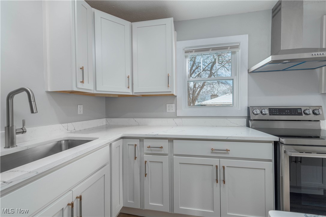 218 Roxboro Road Vermilion, OH 44089 - Photo 17 of 50 Kitchen featuring stainless steel range with electric stovetop, wall chimney exhaust hood, light stone countertops, and white cabinets