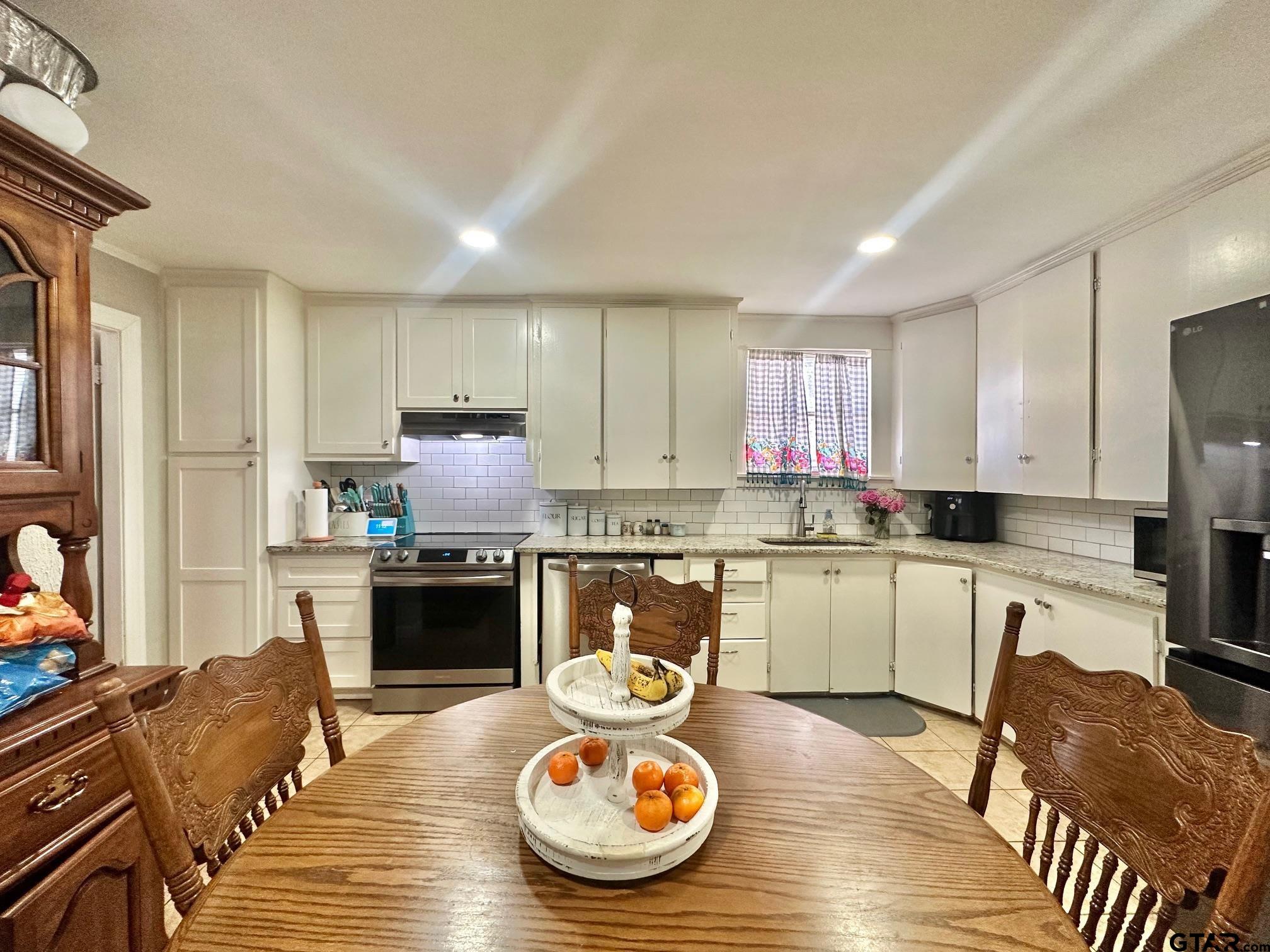 2601 East George Richey Road Longview, TX 75604 - Photo 12 of 26 a kitchen with refrigerator stove dining table and chairs