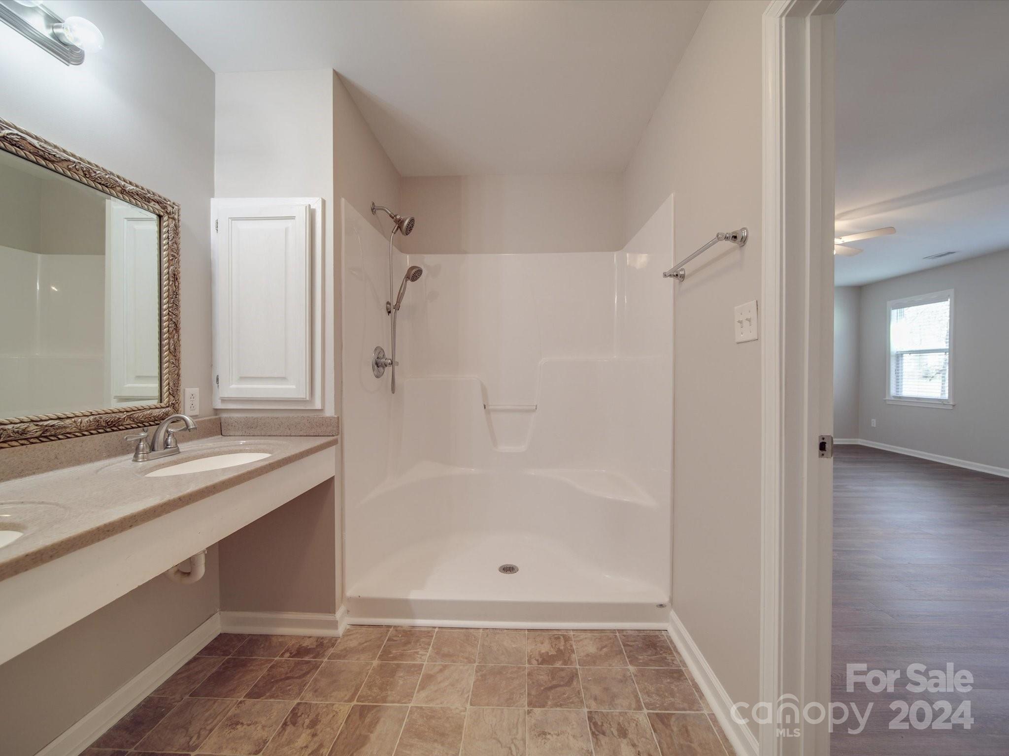 3806 Dusty Hollow Road Monroe, NC 28110 - Photo 10 of 21 a bathroom with a granite countertop sink a mirror and a shower