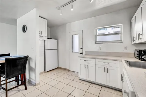 a kitchen with white cabinets and refrigerator
