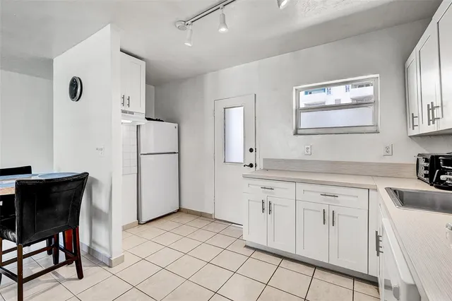a kitchen with white cabinets and refrigerator