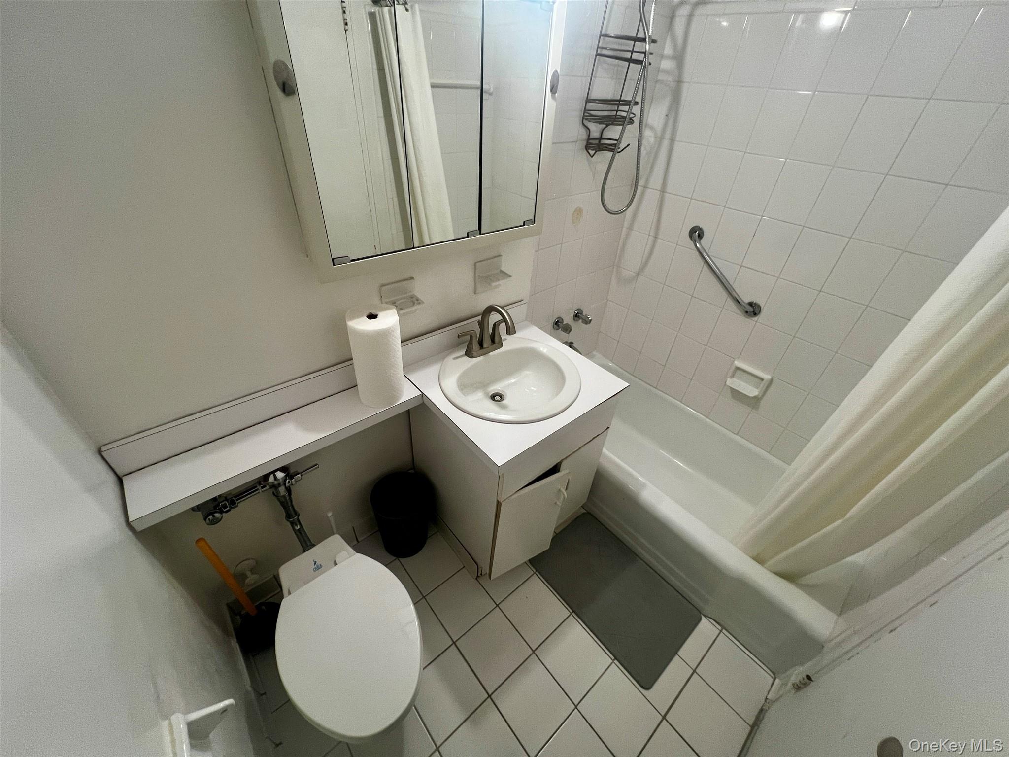 84-29 155th Avenue, Unit 2H Queens, NY 11414 - Photo 23 of 38 Bathroom with vanity, light tile patterned floors, and shower / tub combo with curtain