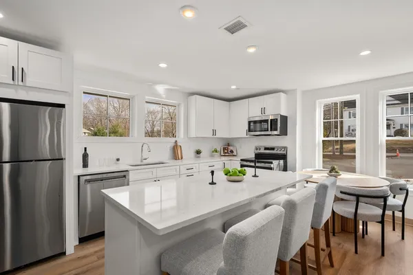 a kitchen with a refrigerator a stove a sink a dining table and chairs