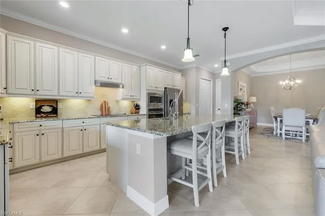 a kitchen with stainless steel appliances kitchen island granite countertop a table chairs sink and cabinets