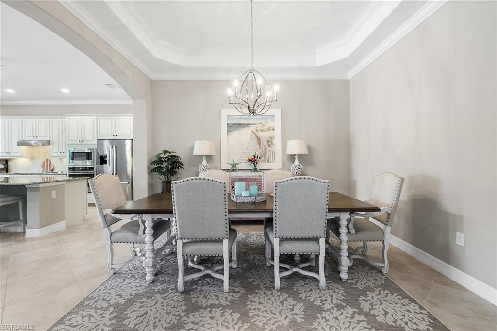 12832 Kinross Lane Naples, FL 34120 - Photo 10 of 45 Dining area featuring arched walkways, crown molding, a chandelier, and light tile patterned floors