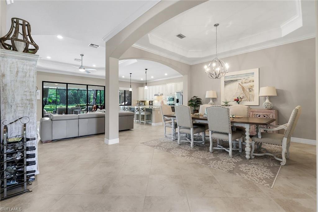 12832 Kinross Lane Naples, FL 34120 - Photo 11 of 45 Dining area featuring a raised ceiling, arched walkways, crown molding, light tile patterned floors, and a ceiling fan