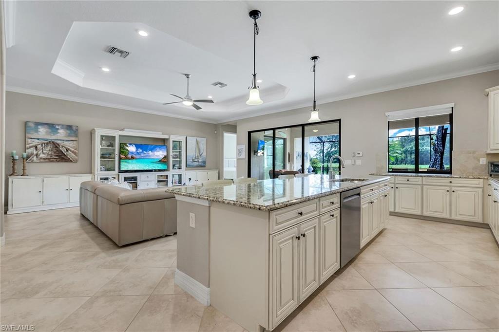 12832 Kinross Lane Naples, FL 34120 - Photo 2 of 45 Kitchen featuring crown molding, decorative light fixtures, light tile patterned flooring, light stone counters, and an island with sink