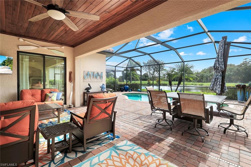 12832 Kinross Lane Naples, FL 34120 - Photo 23 of 45 View of patio, a sunroom, a water view, a ceiling fan, and an outdoor pool