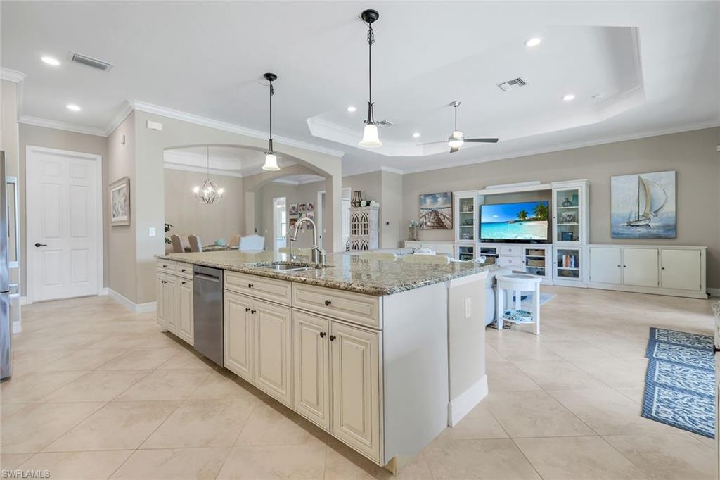 12832 Kinross Lane Naples, FL 34120 - Photo 45 of 45 Kitchen with open floor plan, light stone countertops, a chandelier, crown molding, and light tile patterned flooring