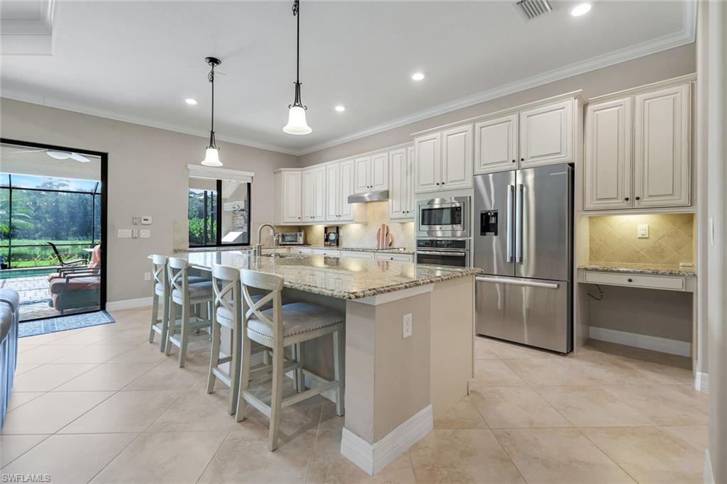 12832 Kinross Lane Naples, FL 34120 - Photo 9 of 45 Kitchen featuring ornamental molding, decorative backsplash, appliances with stainless steel finishes, pendant lighting, and light stone counters