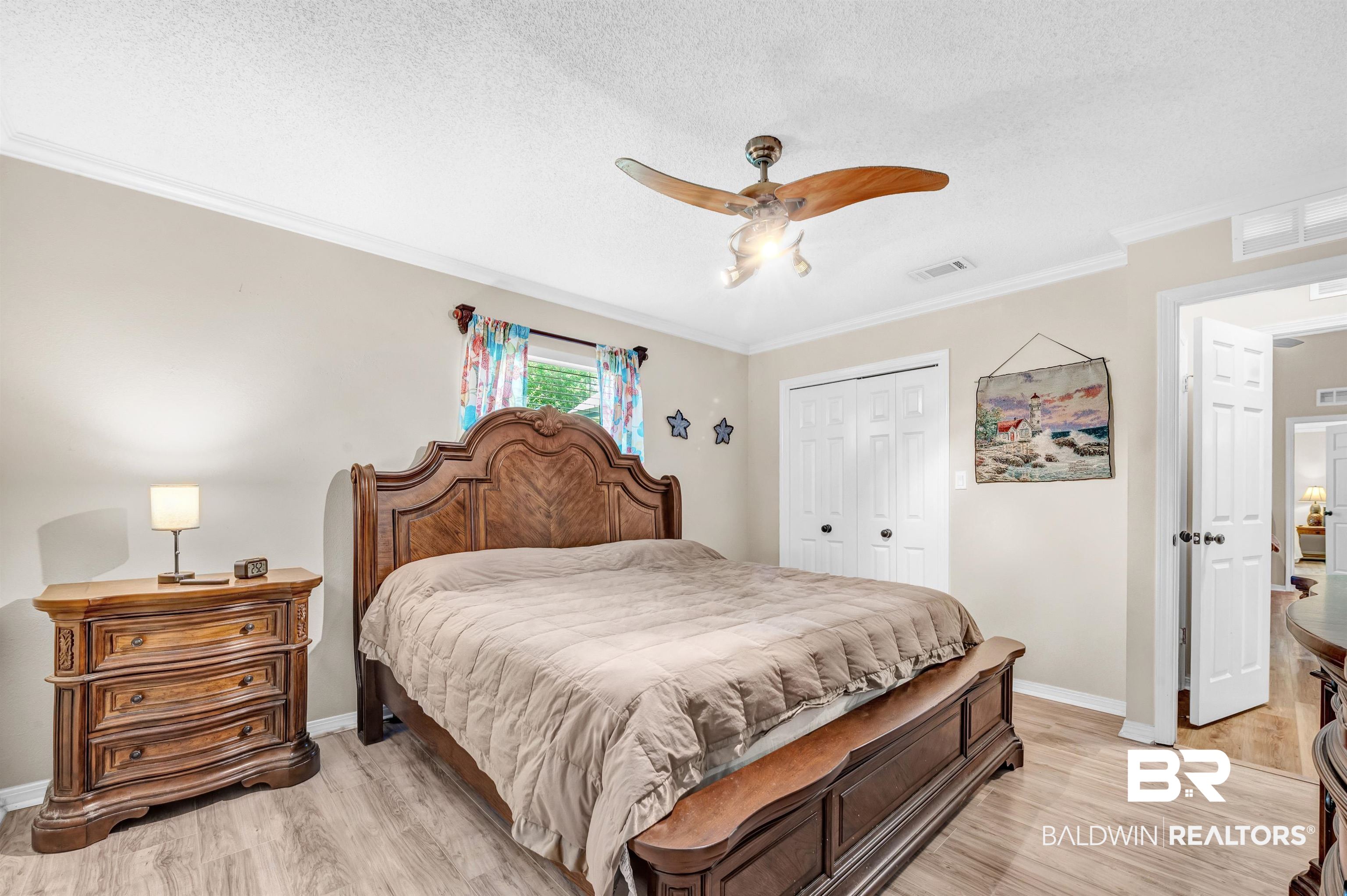 24551 Wolf Bay Drive Foley, AL 36535 - Photo 47 of 59 Bedroom with a closet, light wood finished floors, ornamental molding, a textured ceiling, and ceiling fan
