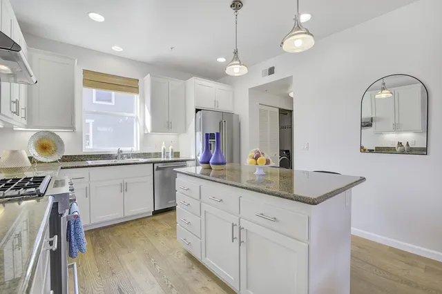 a kitchen with granite countertop a sink a stove refrigerator and cabinets