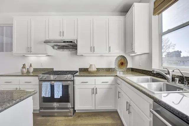 a kitchen with granite countertop a sink stove and cabinets