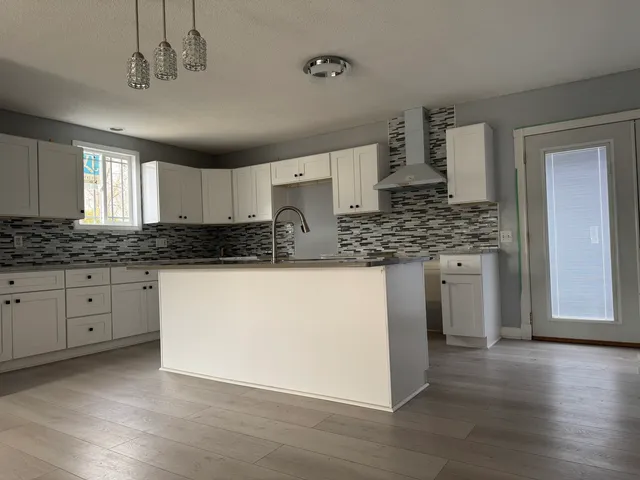 a kitchen with stainless steel appliances granite countertop a stove a sink and white cabinets with wooden floor