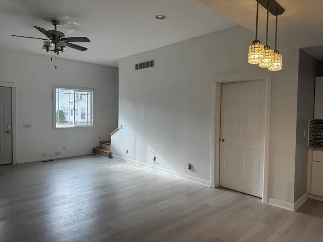 a view of an empty room with a window and wooden floor