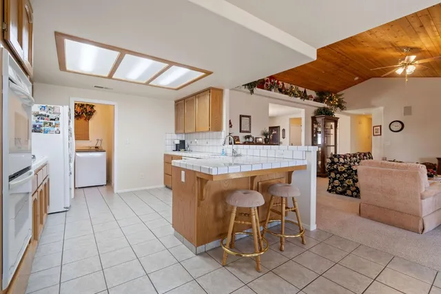 a dining hall with stainless steel appliances kitchen island granite countertop a table chairs and a refrigerator