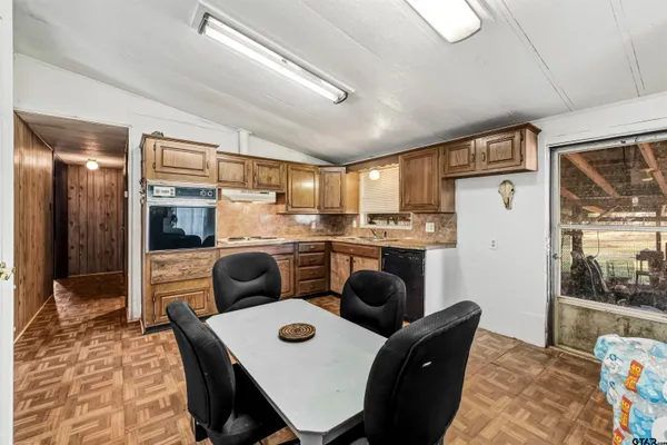 a kitchen with a refrigerator a stove a sink dishwasher a dining table and chairs with wooden floor