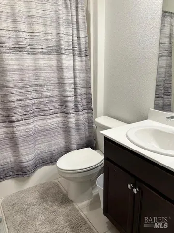 a bathroom with a granite countertop toilet and a sink