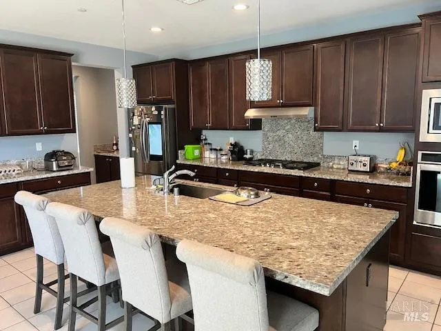 a kitchen with kitchen island granite countertop a table chairs sink and cabinets