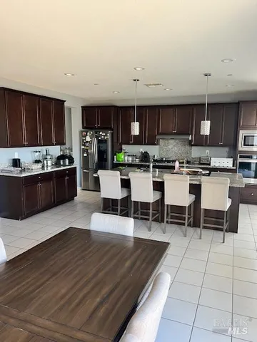 a living room with stainless steel appliances kitchen island granite countertop a sink and cabinets