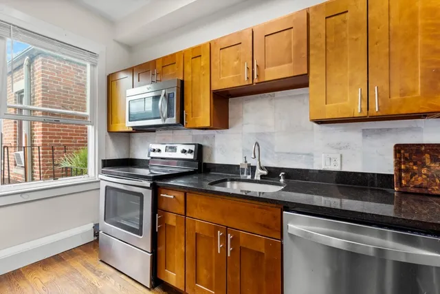 a kitchen with granite countertop cabinets stainless steel appliances a sink and a window