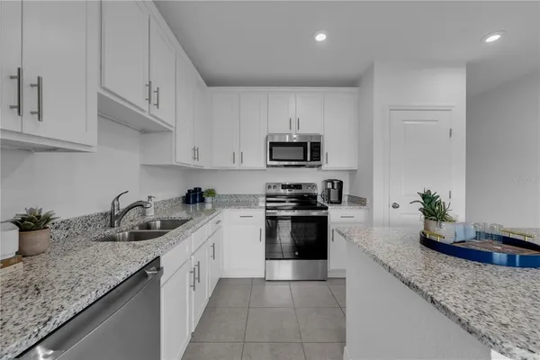 a kitchen with granite countertop a sink dishwasher stove and cabinets with wooden floor