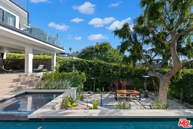 a view of swimming pool with lawn chairs and plants