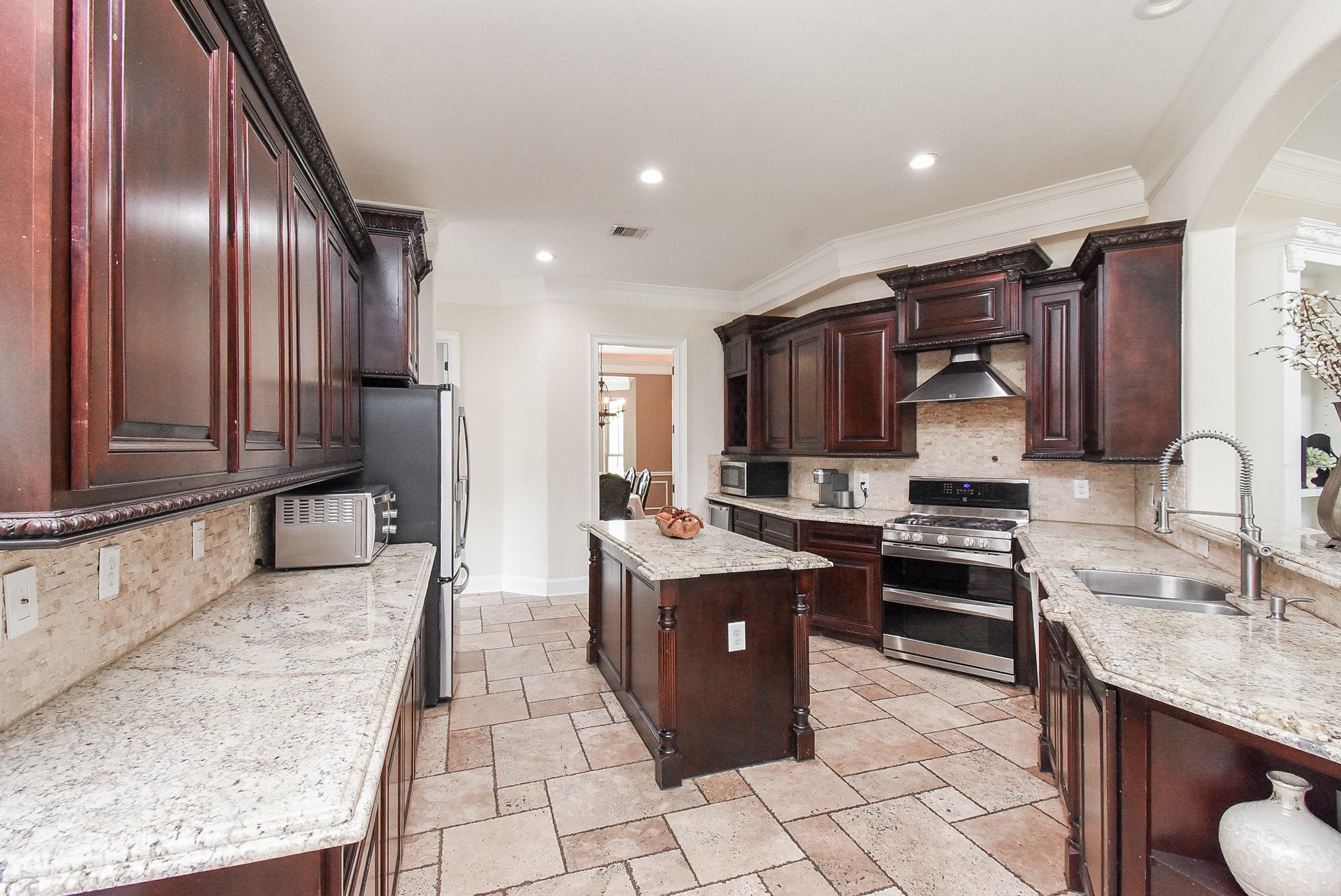 633 Crenshaw Road Houston, TX 77504 - Photo 11 of 46 This kitchen features elegant dark wood cabinetry, granite countertops, and modern stainless steel appliances. It includes a central island, ample counter space, and a stylish tile floor, creating a warm and inviting atmosphere.