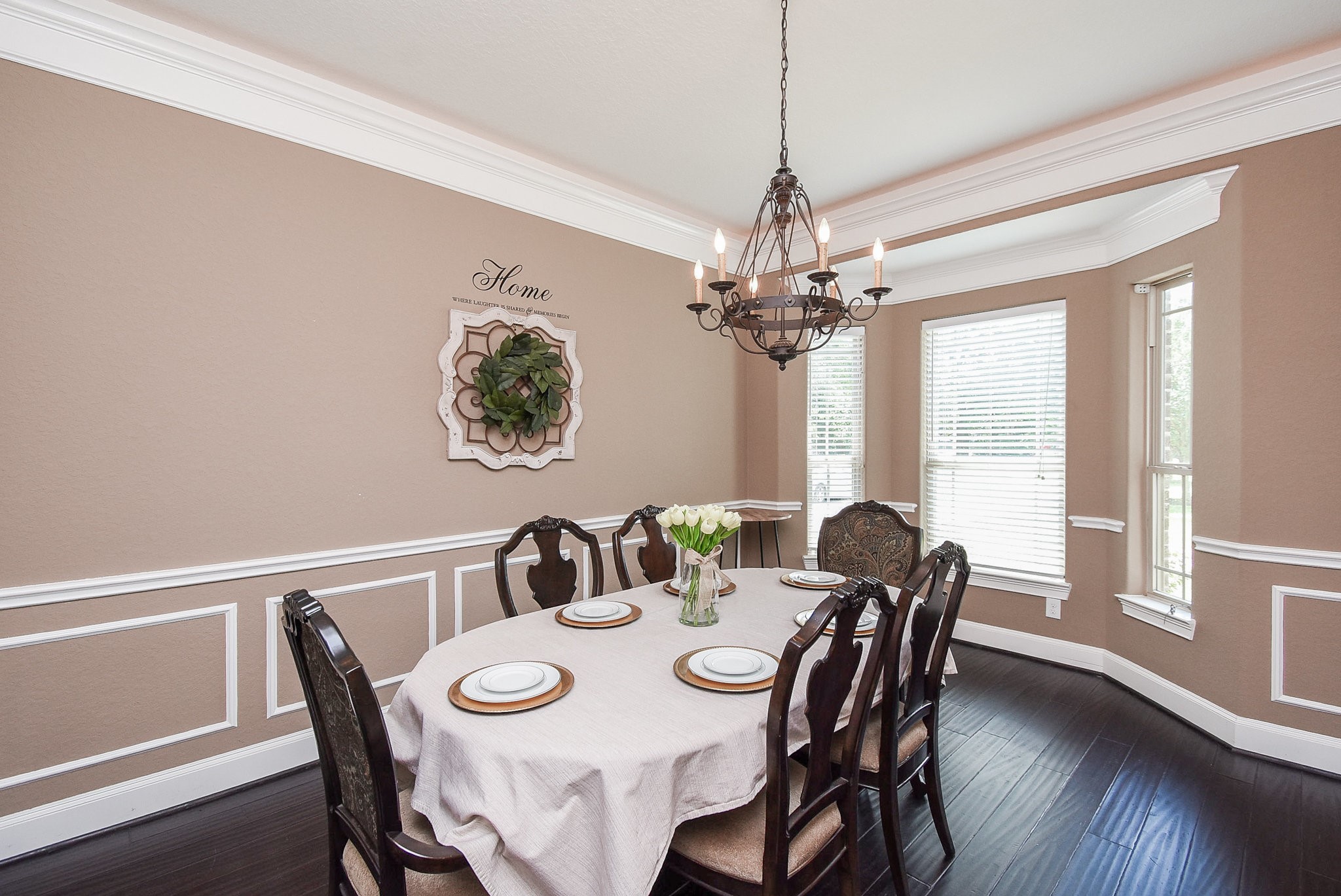 633 Crenshaw Road Houston, TX 77504 - Photo 15 of 46 Elegant dining room with a classic chandelier, large windows for natural light, and tasteful wainscoting. The room features a decorated wall with a warm color palette and a spacious table setup, perfect for gatherings.